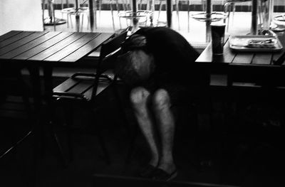 Rear view of woman sitting on table at home