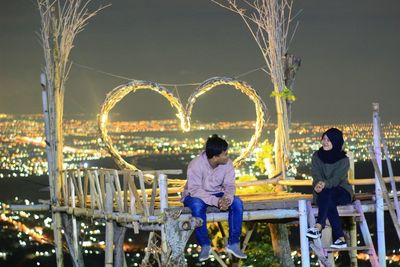 Rear view of couple sitting at illuminated night