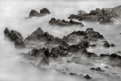 The breaking waves on the rocks look like fog on the mountain range.