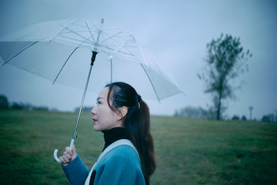 Side view of woman holding umbrella on land