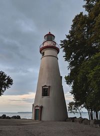 Low angle view of lighthouse by building against sky