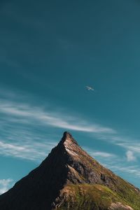 Airplane flying over mountains against blue sky