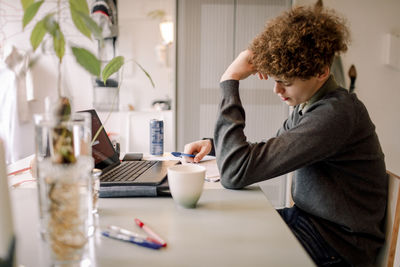 Teenage boy studying while sitting at table