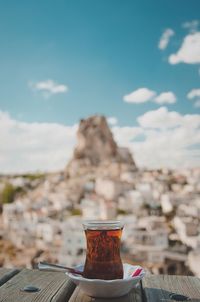 Close-up of drink on table against town