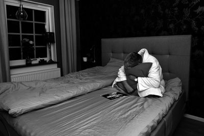 Woman sitting on bed at home