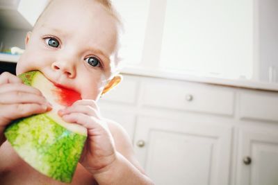 Close-up of baby boy eating watermelon slice at home