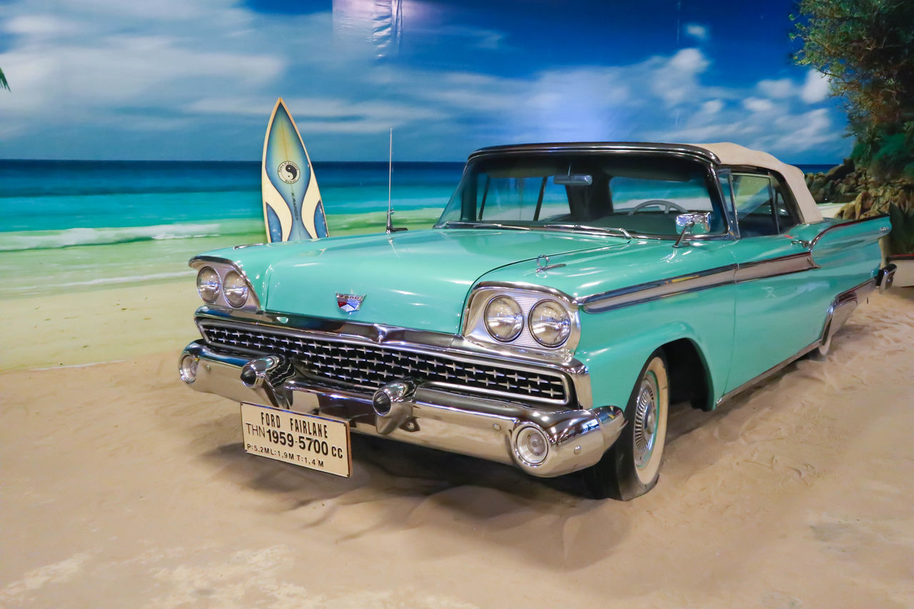 vehicle, car, mode of transportation, transportation, land vehicle, motor vehicle, land, beach, retro styled, sea, sky, vintage car, sand, nature, water, cloud, automotive exterior, travel, blue, collector's car, antique car, vacation, trip, luxury vehicle, outdoors, day, tropical climate
