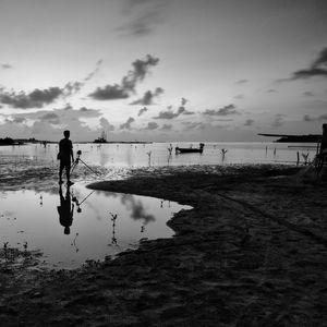 Man on beach against sky during sunset