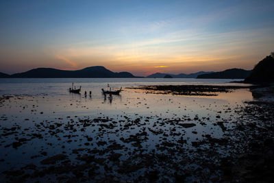 Silhouette people on beach against sky during sunset