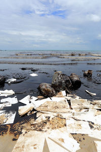 Garbage at beach against cloudy sky