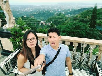 Portrait of couple standing in balcony against trees