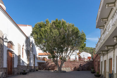 Street amidst buildings in town against clear blue sky