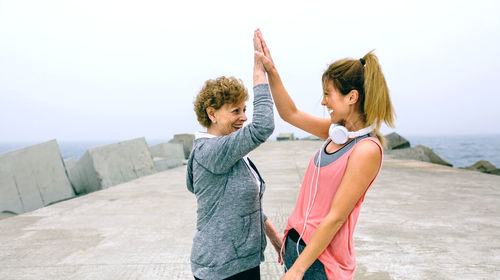 Mother and daughter standing on pier against sky