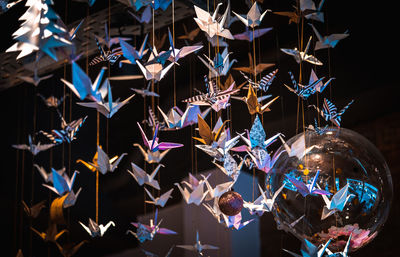 Lots of origami swans hanging from the roof, seen from underneath in a softly illuminated room