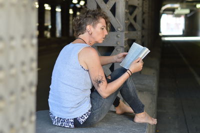 Mature woman reading bible in underpass