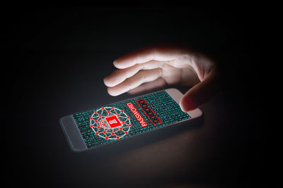 Close-up of hand holding illuminated electric lamp against black background