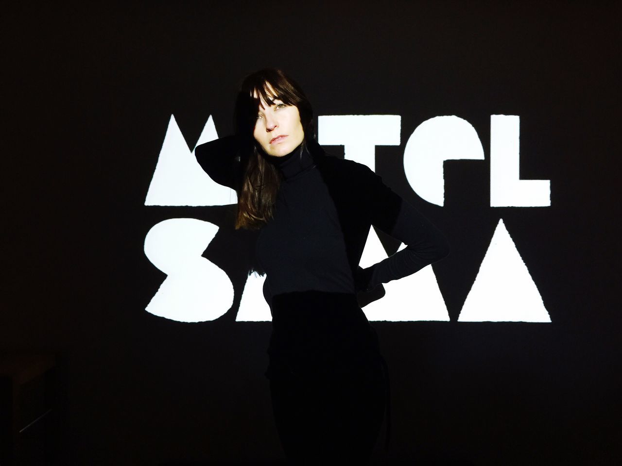 one person, communication, standing, sign, studio shot, indoors, young adult, women, lifestyles, front view, symbol, arrow symbol, real people, black background, black color, adult, three quarter length, waist up, hairstyle, beautiful woman