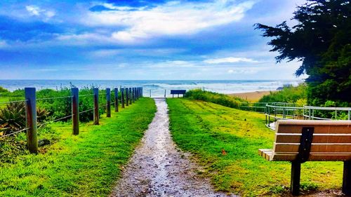 Scenic view of field by sea against sky