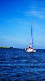 Sailboat sailing in sea against blue sky