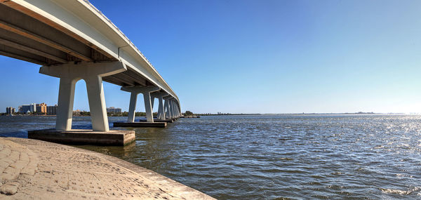 Bridge over sea against clear blue sky