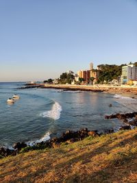 Scenic view of sea and buildings against clear sky