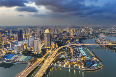 High angle view of illuminated buildings in city against cloudy sky