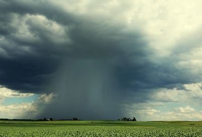 Scenic view of field against storm clouds