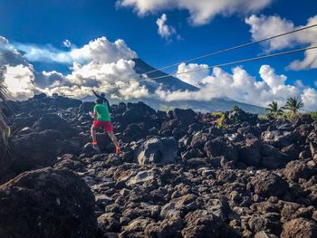 Rear view of man walking on rock against sky