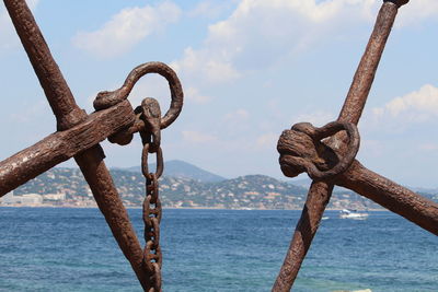 Close-up of rusty metal by sea against sky