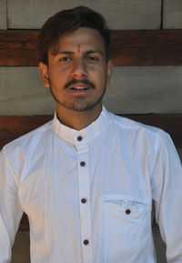 Close-up of a charming indian young guy looking at camera while staging against wall