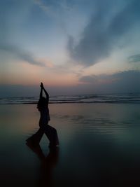 Silhouette girl on beach against sky during sunset