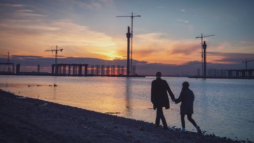 Silhouette of people standing on pier at sunset