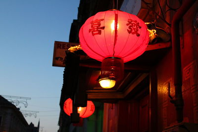 Low angle view of illuminated lanterns hanging against sky