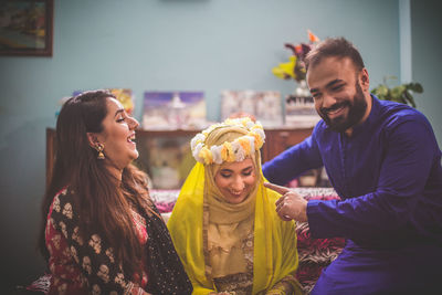 Smiling friends with bride in home