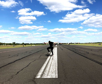 Rear view of man riding motorcycle on road against sky