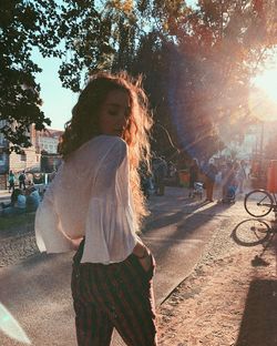 Woman standing by tree in city