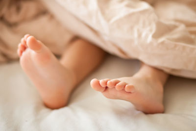 Low section of baby lying on bed