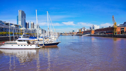 Sailboats moored in sea against sky in city