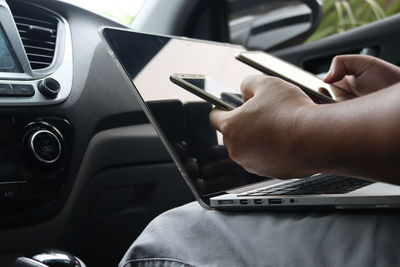 Cropped image of man using technologies while traveling in car