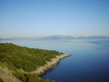 Scenic view of sea and mountains against clear blue sky