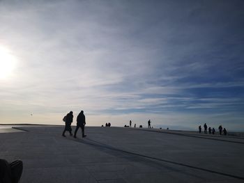 Rear view of people walking on road against sky