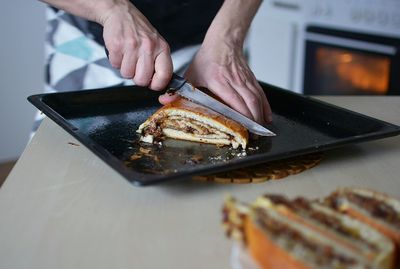 Midsection of person cutting food in kitchen at home