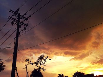 Low angle view of electricity pylon against cloudy sky