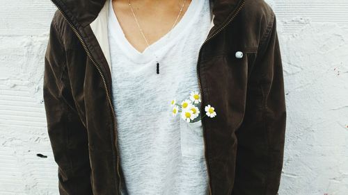 Midsection of woman standing with white daisy flowers in pocket