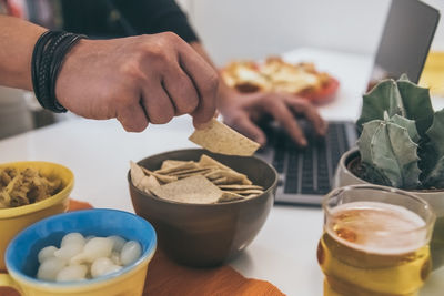 Hand taking finger food using laptop computer. table with foods, aperitif with family and friends