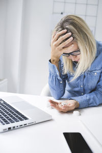 Stressed businesswoman with head in hand sitting at office