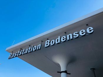 Low angle view of sign against clear blue sky