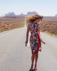 Woman standing with hair blowing in front of monument valley desert