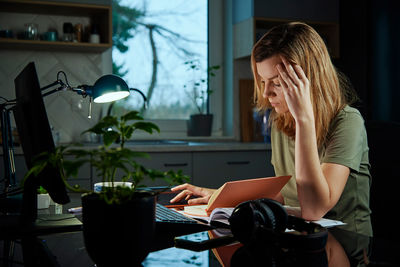 Tired woman works late at home workplace in the night