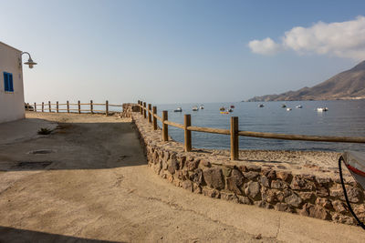 Wooden posts on beach by sea against sky